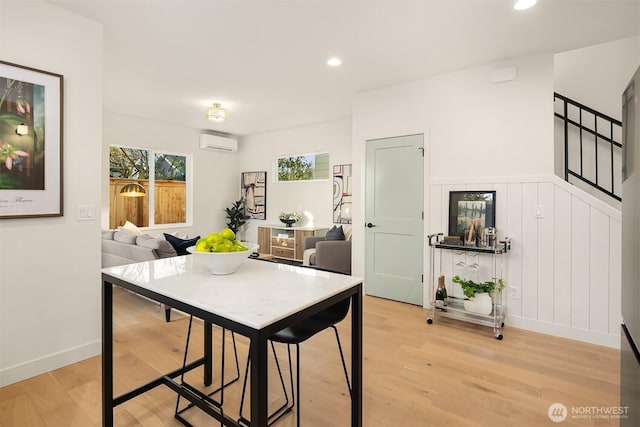 dining area with a wall mounted air conditioner, baseboards, recessed lighting, and light wood finished floors