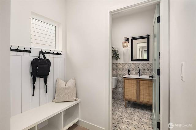 mudroom with tile walls, a wainscoted wall, and a sink