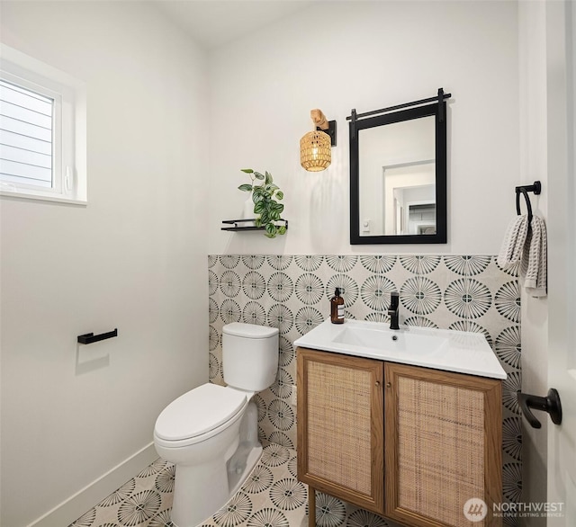 bathroom featuring a wainscoted wall, toilet, tile walls, and vanity