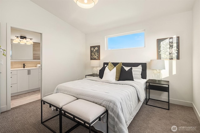 bedroom featuring baseboards, carpet floors, ensuite bath, lofted ceiling, and a sink