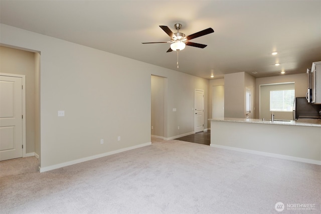 unfurnished living room with carpet, baseboards, recessed lighting, a sink, and ceiling fan