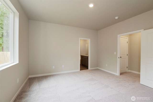 unfurnished bedroom with light colored carpet, baseboards, and multiple windows