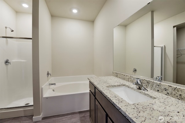 full bath with a bath, a shower stall, vanity, and wood finished floors