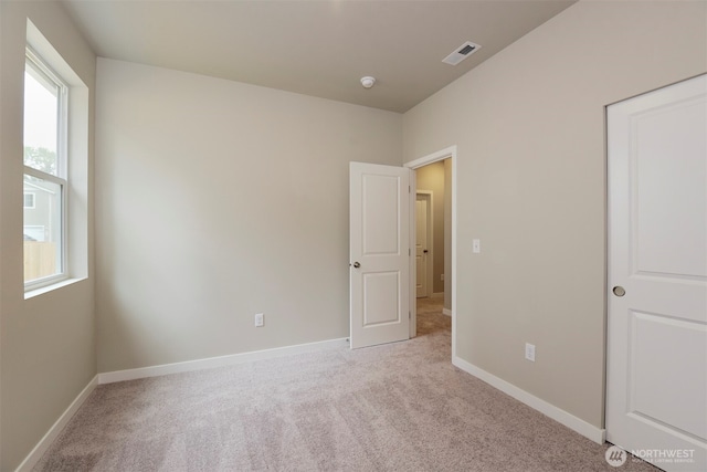 unfurnished bedroom with visible vents, multiple windows, baseboards, and carpet