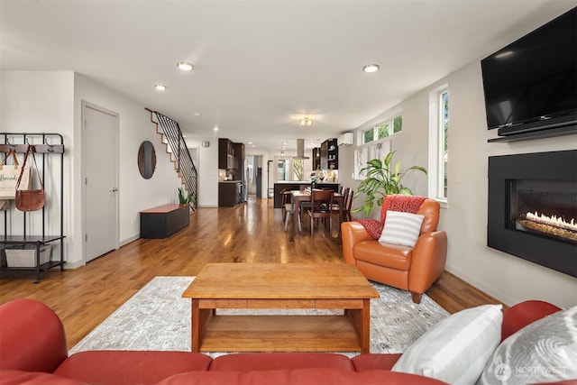 living room featuring a glass covered fireplace, recessed lighting, and wood finished floors