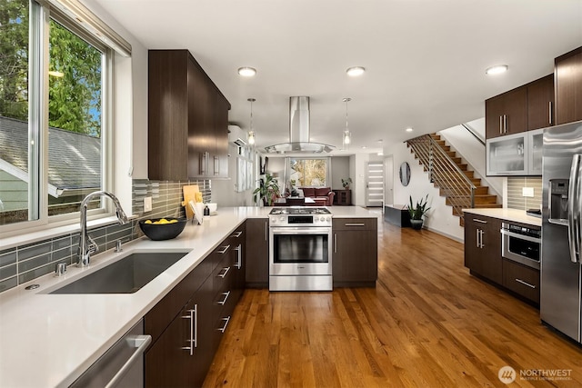 kitchen featuring a sink, light countertops, island range hood, and stainless steel appliances