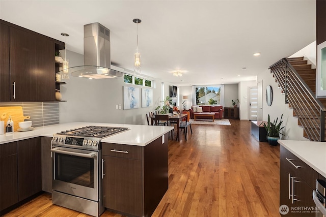 kitchen featuring light countertops, gas stove, a peninsula, and island range hood