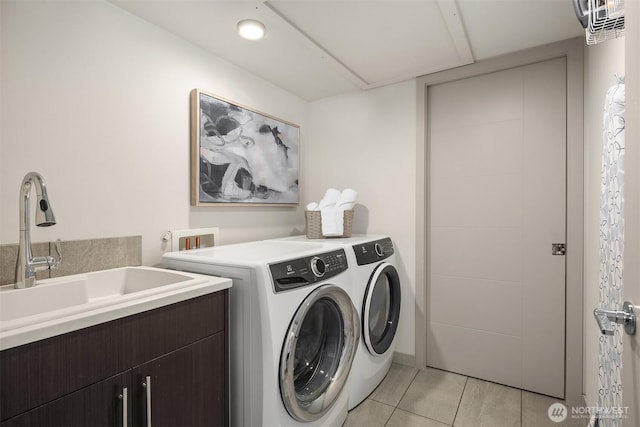 laundry area featuring washing machine and clothes dryer, light tile patterned floors, cabinet space, and a sink