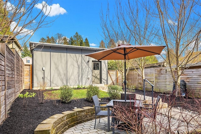 view of patio / terrace with an outbuilding, outdoor dining area, and a fenced backyard