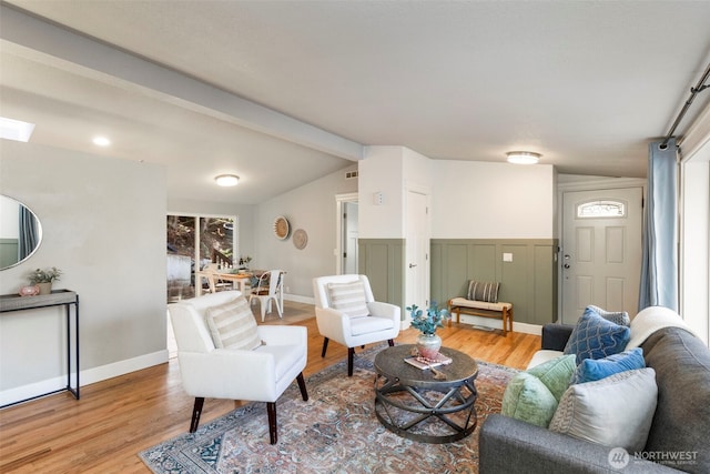 living room featuring visible vents, light wood-style flooring, vaulted ceiling with beams, and baseboards