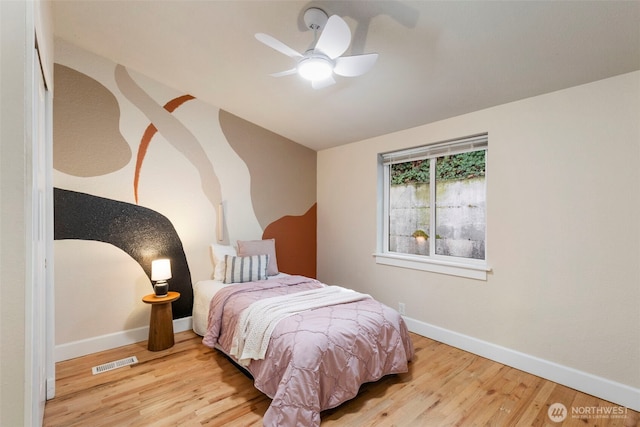 bedroom featuring visible vents, a ceiling fan, baseboards, and wood finished floors