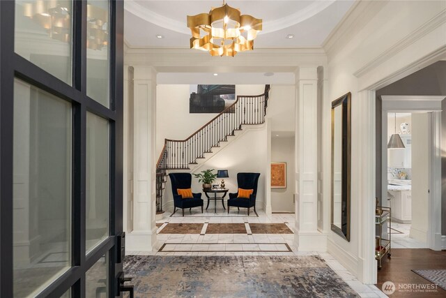 entryway featuring stairway, baseboards, ornate columns, an inviting chandelier, and crown molding