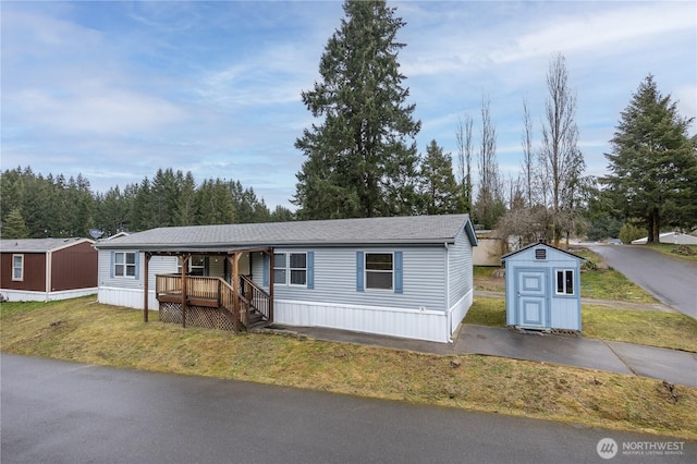 manufactured / mobile home featuring a storage shed, an outdoor structure, and a front lawn