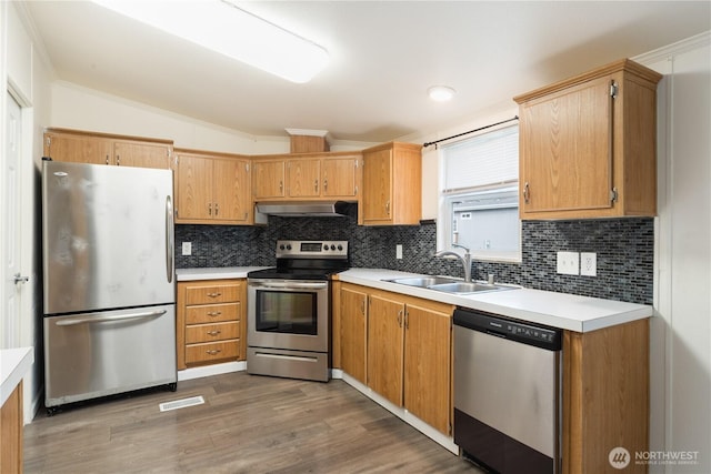 kitchen featuring visible vents, a sink, under cabinet range hood, appliances with stainless steel finishes, and backsplash