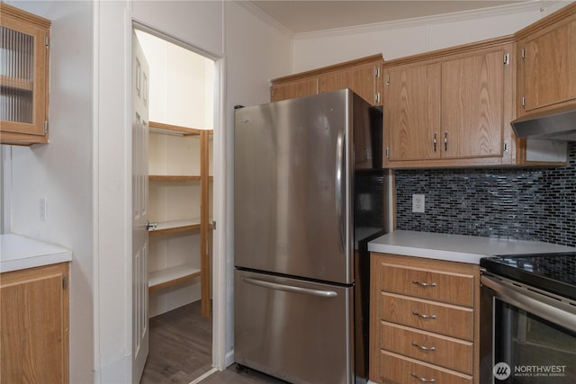 kitchen with brown cabinets, tasteful backsplash, under cabinet range hood, and stainless steel appliances