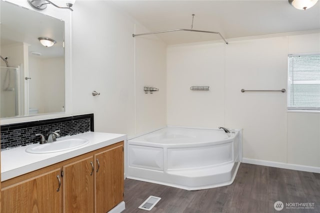 full bathroom featuring visible vents, backsplash, wood finished floors, bathing tub / shower combination, and vanity