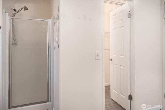 bathroom with a shower stall and wood finished floors