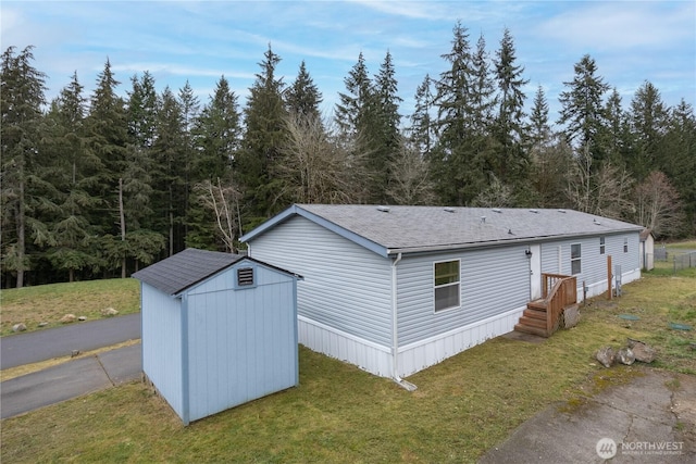 exterior space featuring a lawn, a shingled roof, a storage shed, and an outdoor structure