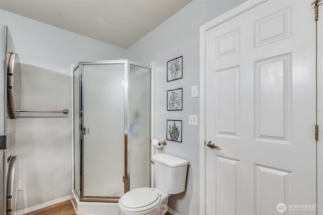 full bath with a shower stall, toilet, and baseboards