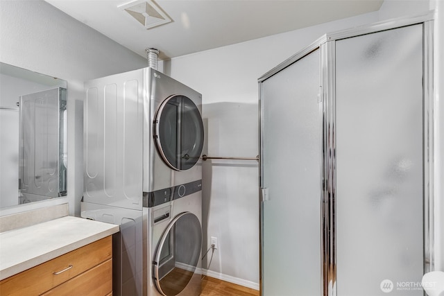 clothes washing area with light wood-style floors, laundry area, visible vents, and stacked washer and clothes dryer