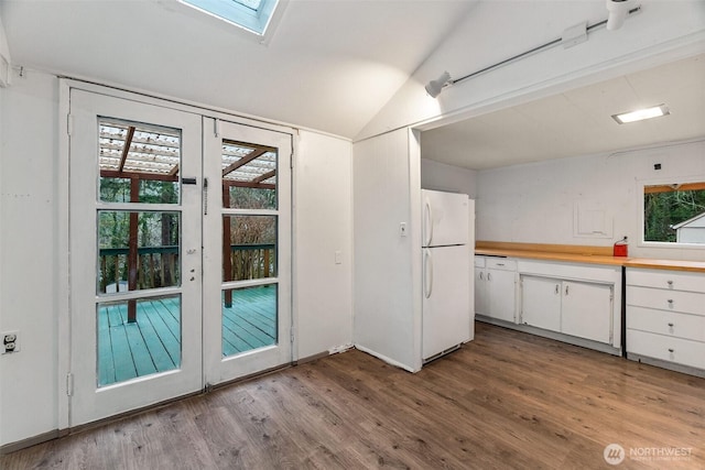 kitchen featuring wood finished floors, wooden counters, freestanding refrigerator, white cabinets, and lofted ceiling with skylight