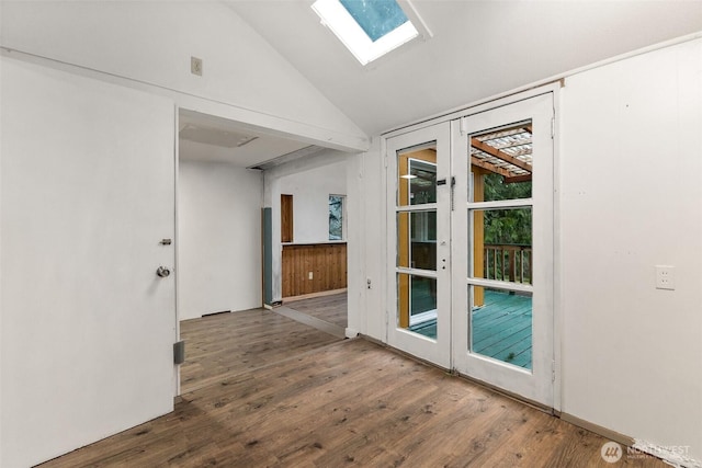 interior space with vaulted ceiling with skylight, french doors, and wood finished floors