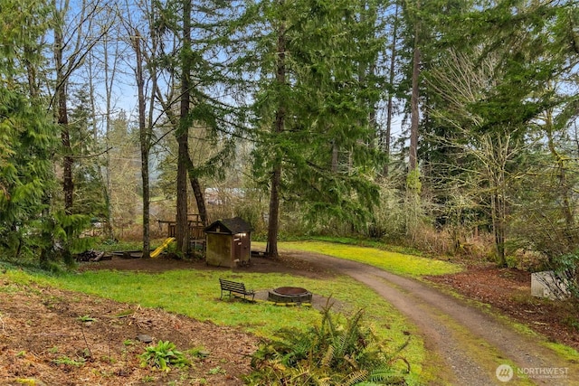 surrounding community with an outbuilding, driveway, a fire pit, a storage shed, and a lawn