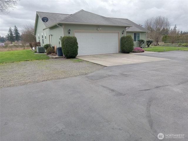 view of side of home with driveway, a yard, an attached garage, a shingled roof, and central AC unit