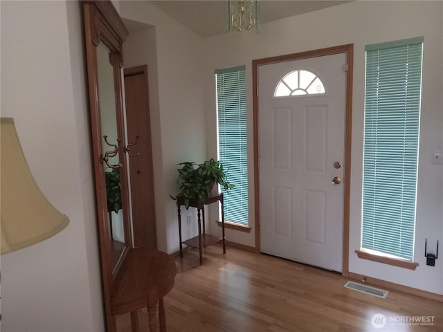 entrance foyer with an inviting chandelier, light wood-style flooring, and visible vents