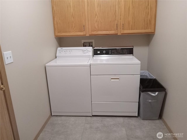 clothes washing area with cabinet space, baseboards, and separate washer and dryer