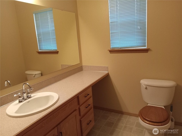 half bath with vanity, toilet, and baseboards