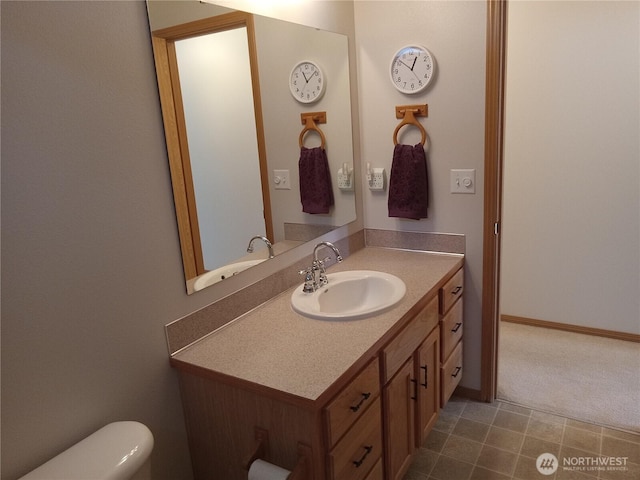 bathroom with baseboards, toilet, and vanity