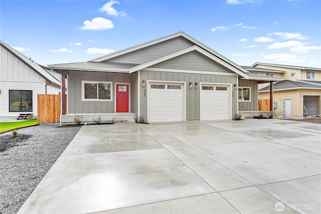 view of front of property featuring driveway, board and batten siding, an attached garage, and fence