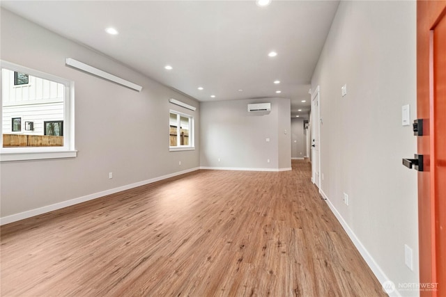 unfurnished room featuring recessed lighting, a wall mounted air conditioner, light wood-style flooring, and baseboards