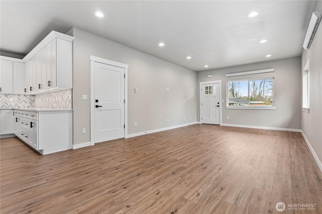 unfurnished living room with light wood-style flooring, recessed lighting, and baseboards