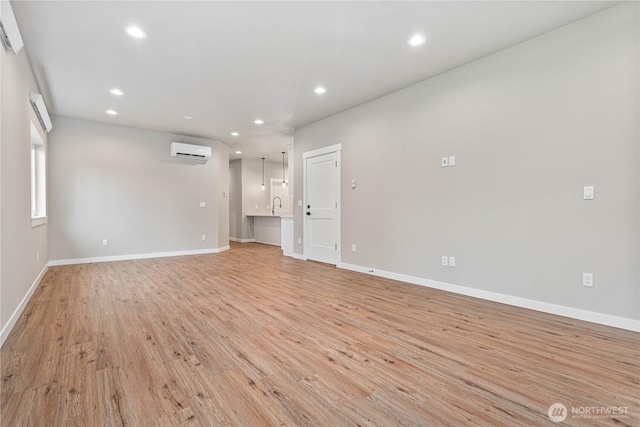 empty room with light wood-style flooring, recessed lighting, baseboards, and a wall mounted AC