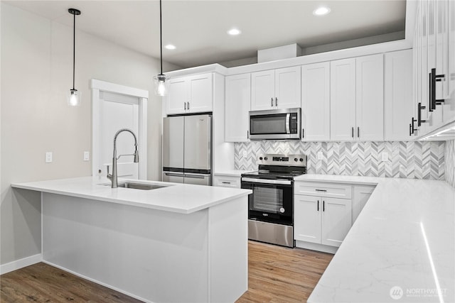 kitchen featuring light wood-type flooring, tasteful backsplash, appliances with stainless steel finishes, and a sink