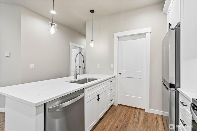 kitchen with a peninsula, a sink, stainless steel appliances, white cabinets, and light wood-type flooring