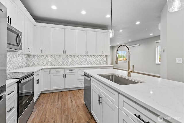 kitchen with backsplash, hanging light fixtures, white cabinets, stainless steel appliances, and a sink