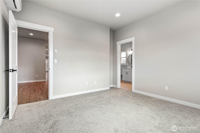 unfurnished bedroom with recessed lighting, baseboards, carpet floors, and a wall mounted air conditioner