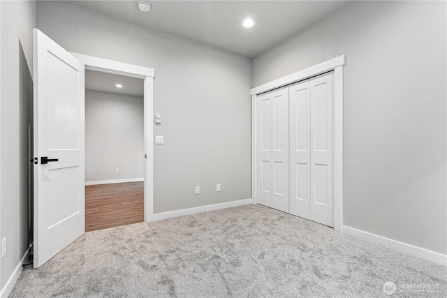 unfurnished bedroom with recessed lighting, baseboards, carpet floors, and a closet