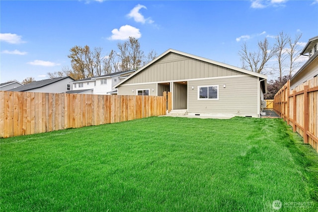 rear view of house with a lawn and a fenced backyard