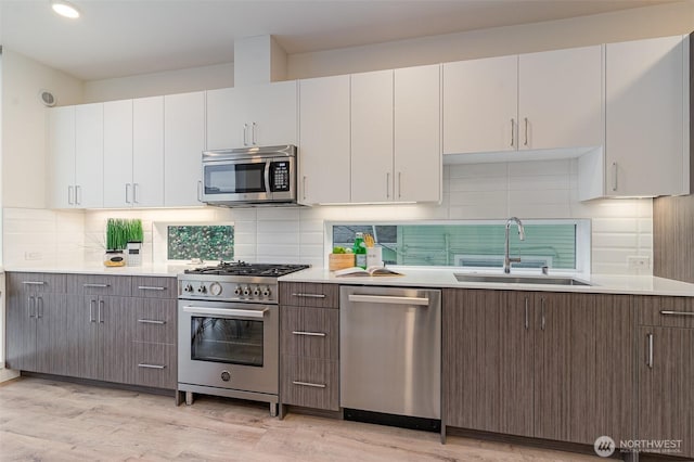 kitchen featuring light wood-style flooring, appliances with stainless steel finishes, light countertops, and a sink