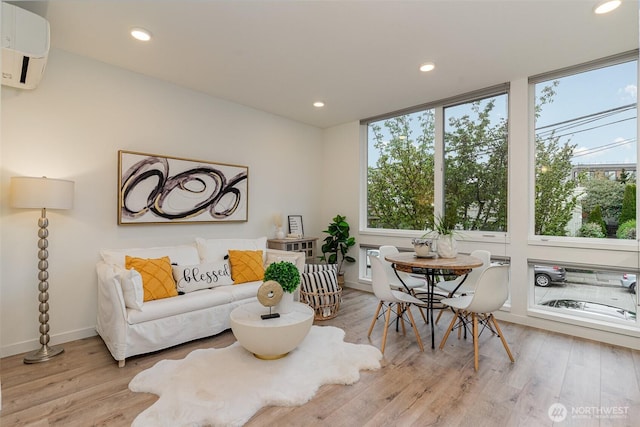 living area featuring an AC wall unit, recessed lighting, light wood-style floors, and baseboards