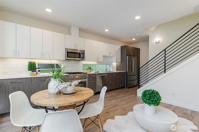 dining area with recessed lighting, light wood-style floors, and stairs