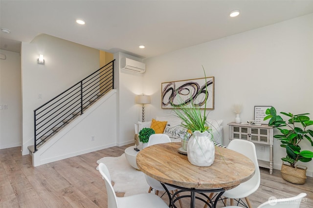 dining area featuring stairs, a wall unit AC, light wood-style flooring, and recessed lighting