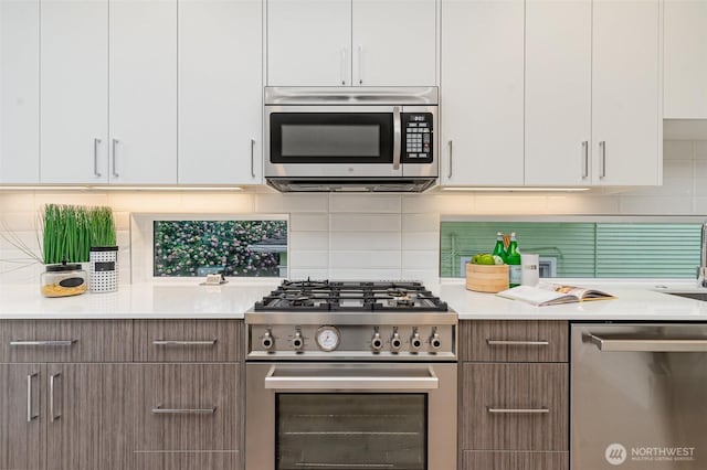 kitchen featuring decorative backsplash, white cabinets, stainless steel appliances, and light countertops