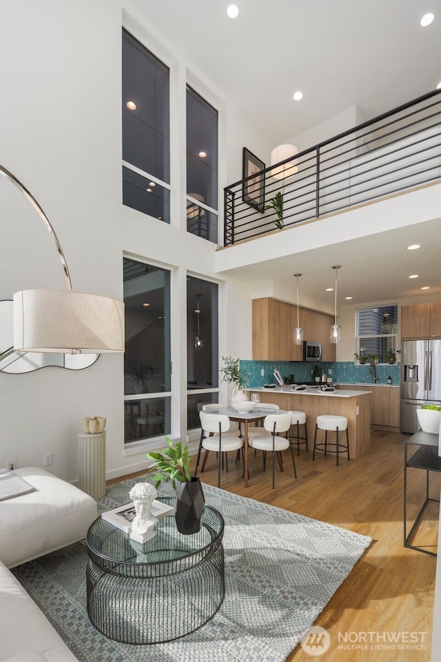 living room featuring light wood finished floors, recessed lighting, and a high ceiling