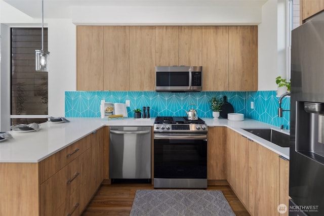 kitchen featuring dark wood-style floors, a sink, light countertops, appliances with stainless steel finishes, and modern cabinets