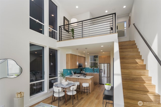 interior space featuring a kitchen bar, brown cabinetry, light wood finished floors, and stainless steel appliances